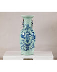 Cobalt blue and white porcelain vase with scholar images, displayed on a white pedestal against a plain background.