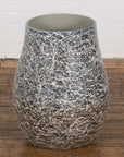 Black, white, and gray ceramic planter vase with abstract splatter pattern on wooden floor.