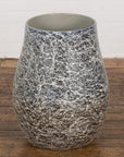 Black, white, and gray ceramic planter vase with abstract splatter pattern on wooden floor.