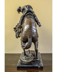 Bronze Frederic Remington "Rattlesnake" tabletop statue of cowboy on bucking horse, Western art style, on table.