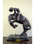 Bronze Frederic Remington "Rattlesnake" tabletop statue of cowboy on bucking horse, Western art style, on table.