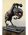 Bronze Frederic Remington "Rattlesnake" tabletop statue of cowboy on bucking horse, Western art style, on table.