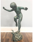 Bronze sculpture of a child balancing on a large snail, garden fountain, outdoor setting.