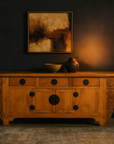 Dark wood Qing Dynasty 19th-century sideboard with large carved spandrels, topped with art, bowl, and jug against dark wall.