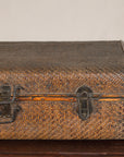 Brown woven rattan suitcase trunk with iron hardware on dark wooden table, Late Qing Dynasty style.