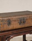 Brown rattan suitcase trunk with iron hardware on a dark wooden table, Late Qing Dynasty style.