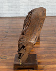 Brown wood arch sculpture with hand-carved animal and floral motifs on a dark antique chest.