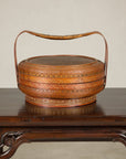 Painted vintage rattan basket on dark wood table.