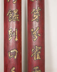 Close-up of raised gilt Chinese characters on the red wood panel surfaces