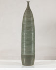Green-glazed ribbed ceramic vase on white surface.