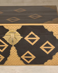 Black lacquered Chinese chest with gold geometric design and brass lock, displayed on a light-colored surface.