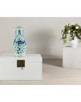 Close-up of an antique Chinese blue and white porcelain vase with scenes and celadon glaze beside a cobalt blue vase.