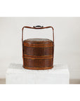 Brown vintage woven carrying box with double handles on a white pedestal, plain background.