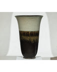 Close-up of large green-grey and brown drip-glazed ceramic planter with flared rim and artisan details.