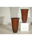 Brown ceramic vases with subtle red undertones on a light floor next to a white pedestal.