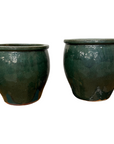 Two dark green ceramic pots on a white background