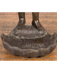 Dark patina bronze winged cherub statue standing on a shell, lost wax cast, close-up view.