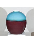 Turquoise and brown ceramic vase on white pedestal.