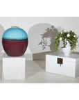 Turquoise and brown round ceramic vase next to white chest and floral white vase on display.