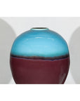Close-up of round ceramic vase with turquoise glaze fading into brown, displayed on a plain white background.