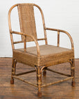 Brown hand-woven rattan armchair with rounded back on wooden floor against a white brick wall, country style.
