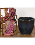 Colorful fabric wooden chair beside Thai vintage oversized Shigaraki style Namako glazed planter, indoor setting.
