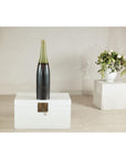 Charcoal ceramic vase with moss green glazed neck on white chest; white vase with green flowers in background.