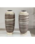 Close-up of two tall ceramic vases with horizontal swirl designs on a white surface against a neutral background.