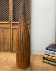 Sand brown and orange ceramic vase with black crackle design on wooden table next to a stack of books.