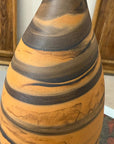 Close-up of orange vase with black swirl, tall and skinny, ceramic, on wooden background.