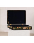 Close-up of a black lacquer box with floral and bird design, felt interior, open on a white pedestal.