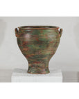 Green, brown, and red ceramic planter in vintage style on a white pedestal against a plain background.