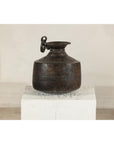 Vintage silver hand-hammered metal jug with ring handle on a white pedestal.