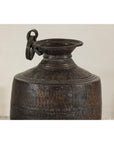 Close-up of a silver hand-hammered metal jug with ring handle, wide spout, and textured finish.
