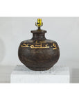 Close-up of vintage dark patina metal jug lamp with yellow script and brass socket, suitable for boho style decor.