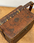 The Woven Rectangular Picnic Basket with Handle & Hinged Lid features metal accents and a rustic brown-and-yellow pattern, highlighting Southeast Asian craftsmanship as it sits on a wooden surface.
