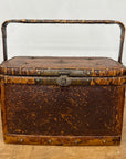 The Woven Rectangular Picnic Basket with Handle & Hinged Lid sits on a wooden surface, its textured brown finish and metal latch showcasing vintage Southeast Asian craftsmanship and rustic charm.