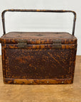 The Woven Rectangular Picnic Basket with Handle & Hinged Lid, crafted from brown rattan with two metal clasps, highlights Southeast Asian artistry as it rests on a wooden surface against a plain light background.