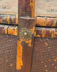 Close-up of the Woven Rectangular Picnic Basket with Handle & Hinged Lid, featuring wood trim and an ornate metal fastener. The chipped finish reveals lighter wood underneath, highlighting its Southeast Asian craftsmanship and unique history.