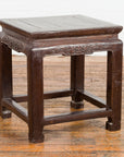 Brown lacquer wood low table with carved apron and horse hoof legs, Qing Dynasty style, on wooden floor.
