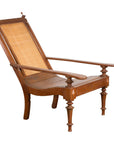 Brown wood and rattan Dutch Colonial lounge chair with caned seat, flat arms, angled recline, and carved finials.