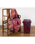 Red and blue Chinese ceramic planter with vintage design beside wooden chair with patterned fabric on wooden floor.