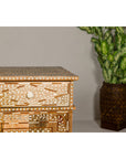 Brown mango wood and white bone inlay buffet in Anglo style, placed beside a leafy green plant.
