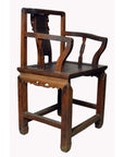 Brown yumu wood official's chair with hand-carved splat and fretwork, antique Chinese furniture, indoor setting.