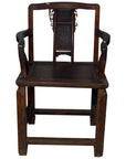 Brown wood Yumu chair with hand-carved splat, fretwork, armrests, and rectangular seat, shown indoors.