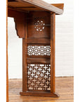 Brown wood Qing Dynasty altar table with bamboo accents, fretwork, everted flanges, on wood floor by white brick wall.