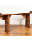 Dark wood Qing Dynasty altar table with bamboo accents, fretwork, and everted flanges on wooden floor by white brick wall.