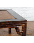 Close-up of dark wood Ming Dynasty style coffee table with hand-woven rattan top on wood floor by white brick wall.
