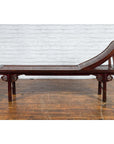 Brown elm and bamboo Qing Dynasty lounge chair with cloud-carved spandrels, white brick wall and wood floor background.