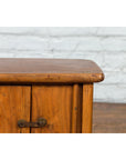 Close-up of a dark wood Qing Dynasty bedside cabinet with tapering lines, against a white brick wall and wood floor.